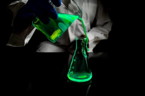 esperimento con una soluzione verde fluorescente in un laboratorio buio