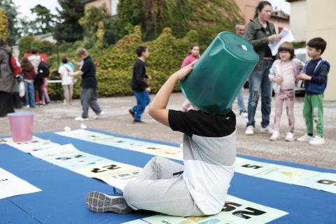Bambino che gioca al turist'oca con un secchio in testa
