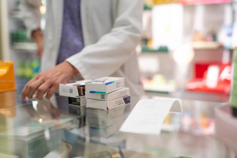 Farmaci impilati sul bancone della farmacia, pronti per la vendita.