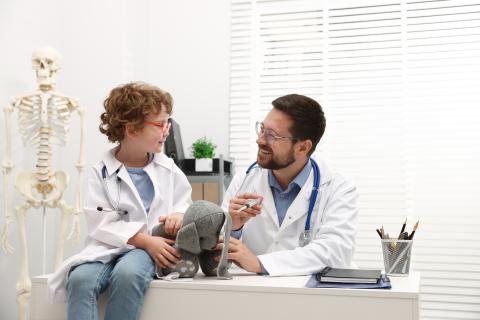 medico e bambino con coniglietto giocattolo che gioca a medico in clinica